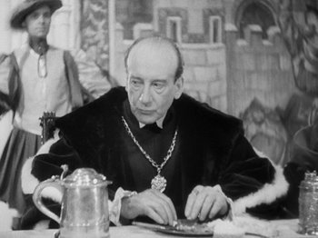 Movie still from “The Private Life of Henry VIII” (1933), directed by Alexander Korda – An older man sitting at a table with a plate in front of him; Close Up shot, Over the shoulder angle