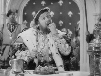 Movie still from “The Private Life of Henry VIII” (1933), directed by Alexander Korda – An old photo of a man sitting at a table eating food; Medium shot, Over the shoulder angle