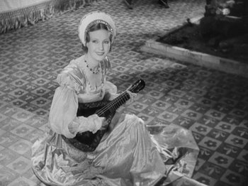 Movie still from “The Private Life of Henry VIII” (1933), directed by Alexander Korda – A woman sitting on the ground holding a guitar; Medium shot, High angle