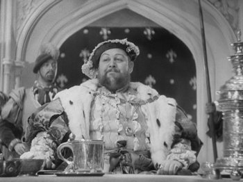 Movie still from “The Private Life of Henry VIII” (1933), directed by Alexander Korda – A man sitting at a table with a glass of wine; Medium shot, Over the shoulder angle