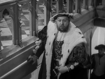 Movie still from “The Private Life of Henry VIII” (1933), directed by Alexander Korda – A man dressed as a king standing next to a railing; Medium shot, High angle