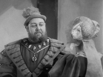 Movie still from “The Private Life of Henry VIII” (1933), directed by Alexander Korda – A man wearing a hat and holding a sword in his hand; Close Up shot, Over the shoulder angle