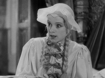 Movie still from “The Private Life of Henry VIII” (1933), directed by Alexander Korda – A woman with long braids wearing a white hat; Medium shot, High angle