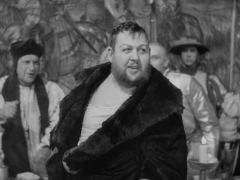 Movie still from “The Private Life of Henry VIII” (1933), directed by Alexander Korda – A man with a beard and a fur coat in front of a group of people; Medium shot, Over the shoulder angle