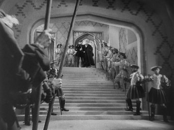 Movie still from “The Private Life of Henry VIII” (1933), directed by Alexander Korda – A black and white photo of people on a staircase; Wide shot, High angle