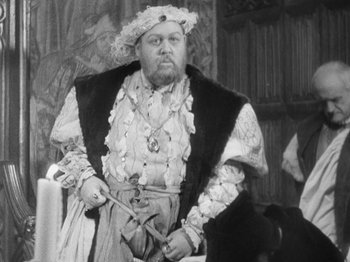 Movie still from “The Private Life of Henry VIII” (1933), directed by Alexander Korda – A man dressed as henry the viii holding a pair of scissors; Medium shot, Over the shoulder angle