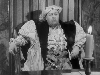Movie still from “The Private Life of Henry VIII” (1933), directed by Alexander Korda – An old photo of a man sitting at a table; Medium shot, High angle