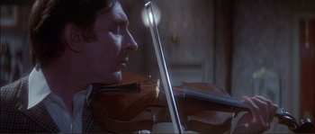 Movie still from “The Private Life of Sherlock Holmes” (1970), directed by Billy Wilder – A man is playing a violin in a room; Close Up shot, Low angle