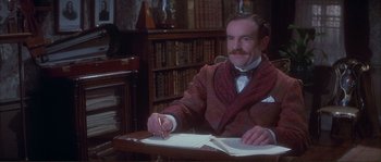 Movie still from “The Private Life of Sherlock Holmes” (1970), directed by Billy Wilder – A man sitting at a desk writing on a piece of paper; Medium shot, High angle