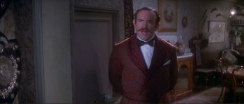 Movie still from “The Private Life of Sherlock Holmes” (1970), directed by Billy Wilder – A man in a suit and bow tie standing next to a door; Medium shot, Over the shoulder angle