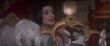 Movie still from “The Private Life of Sherlock Holmes” (1970), directed by Billy Wilder – A woman holding a mirror in front of a lamp; Close Up shot, Over the shoulder angle