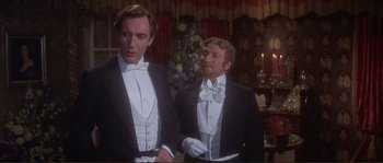 Movie still from “The Private Life of Sherlock Holmes” (1970), directed by Billy Wilder – Two men in tuxedos standing next to each other in front of a christmas tree; Medium shot, Low angle