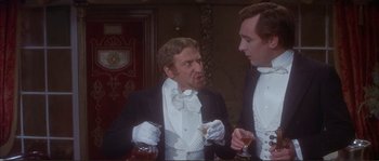 Movie still from “The Private Life of Sherlock Holmes” (1970), directed by Billy Wilder – Two men in tuxedos and white gloves holding drinks; Medium shot, Low angle