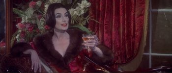 Movie still from “The Private Life of Sherlock Holmes” (1970), directed by Billy Wilder – A woman sitting in a chair holding a glass of wine; Medium shot, Over the shoulder angle