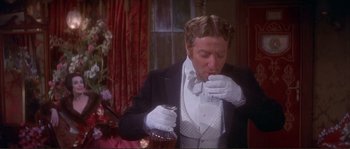 Movie still from “The Private Life of Sherlock Holmes” (1970), directed by Billy Wilder – A man wearing white gloves holding a glass of wine; Medium shot, High angle