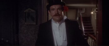 Movie still from “The Private Life of Sherlock Holmes” (1970), directed by Billy Wilder – A man in a top hat with a flower in his hair; Close Up shot, Low angle