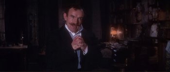 Movie still from “The Private Life of Sherlock Holmes” (1970), directed by Billy Wilder – A man in a black suit and white shirt is posing for a picture; Medium shot, Low angle