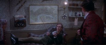 Movie still from “The Private Life of Sherlock Holmes” (1970), directed by Billy Wilder – A man sitting in a chair holding a violin; Medium shot, High angle