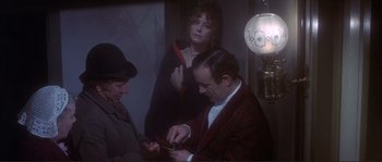 Movie still from “The Private Life of Sherlock Holmes” (1970), directed by Billy Wilder – A man in a red jacket is cutting something with a knife; Medium shot, High angle