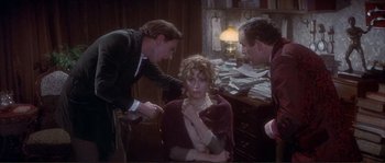 Movie still from “The Private Life of Sherlock Holmes” (1970), directed by Billy Wilder – A woman sitting on a chair in front of two men; Medium shot, High angle