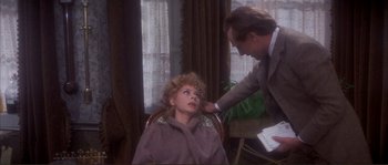 Movie still from “The Private Life of Sherlock Holmes” (1970), directed by Billy Wilder – An older man touching a woman's hair in front of a window; Medium shot, High angle