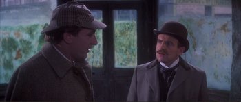 Movie still from “The Private Life of Sherlock Holmes” (1970), directed by Billy Wilder – A man in a suit and a hat talking to another man in a hat; Close Up shot, Over the shoulder angle
