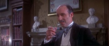 Movie still from “The Private Life of Sherlock Holmes” (1970), directed by Billy Wilder – A man in a suit holding a glass of wine; Close Up shot, Low angle