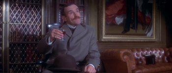 Movie still from “The Private Life of Sherlock Holmes” (1970), directed by Billy Wilder – A man sitting in a chair holding a glass of wine; Medium shot, Low angle