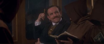 Movie still from “The Private Life of Sherlock Holmes” (1970), directed by Billy Wilder – A man in a suit and tie holding a book and talking on the phone; Medium shot, High angle