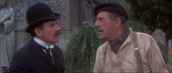 Movie still from “The Private Life of Sherlock Holmes” (1970), directed by Billy Wilder – Two men in hats and suits talking to each other outside; Close Up shot, Over the shoulder angle