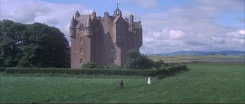 Movie still from “The Private Life of Sherlock Holmes” (1970), directed by Billy Wilder – Two people are walking in a field near a castle; Extreme Wide shot, High angle