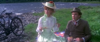 Movie still from “The Private Life of Sherlock Holmes” (1970), directed by Billy Wilder – A woman sitting on the grass with a plate of food in her hands; Medium shot, High angle