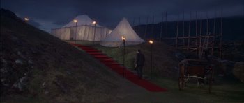 Movie still from “The Private Life of Sherlock Holmes” (1970), directed by Billy Wilder – A man standing on a red carpet in front of tents; Extreme Wide shot, High angle