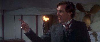 Movie still from “The Private Life of Sherlock Holmes” (1970), directed by Billy Wilder – A man wearing a suit and tie holding something up; Close Up shot, Over the shoulder angle