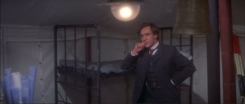 Movie still from “The Private Life of Sherlock Holmes” (1970), directed by Billy Wilder – A man in a suit standing in front of a bed; Medium shot, Low angle