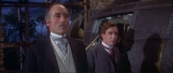 Movie still from “The Private Life of Sherlock Holmes” (1970), directed by Billy Wilder – A man and a man in a suit standing next to each other in front of a train; Medium shot, Low angle