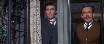 Movie still from “The Private Life of Sherlock Holmes” (1970), directed by Billy Wilder – A man in a suit and tie standing next to a window; Medium shot, Low angle