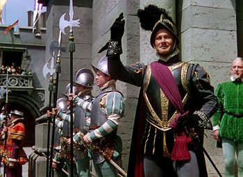 Movie still from “The Private Lives of Elizabeth and Essex” (1939), directed by Michael Curtiz – A group of men dressed in medieval garb; Wide shot, Low angle