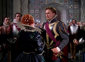 Movie still from “The Private Lives of Elizabeth and Essex” (1939), directed by Michael Curtiz – A man and a woman dressed in medieval garb in front of a crowd; Medium shot, Over the shoulder angle