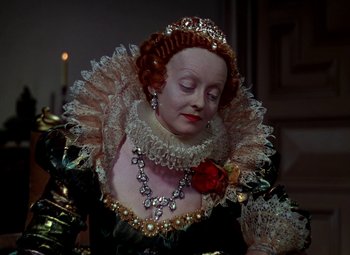 Movie still from “The Private Lives of Elizabeth and Essex” (1939), directed by Michael Curtiz – An older woman wearing a black dress with a rose in her hair; Close Up shot, High angle