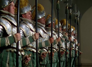 Movie still from “The Private Lives of Elizabeth and Essex” (1939), directed by Michael Curtiz – A group of men dressed in green and silver uniforms holding poles; Wide shot, Low angle