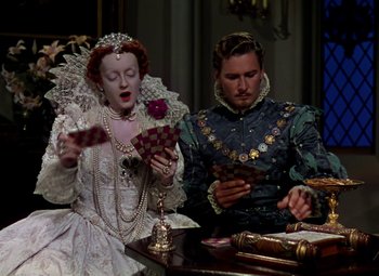 Movie still from “The Private Lives of Elizabeth and Essex” (1939), directed by Michael Curtiz – A man and a woman sitting at a dinner table; Medium shot, High angle