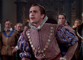 Movie still from “The Private Lives of Elizabeth and Essex” (1939), directed by Michael Curtiz – A man in a red and white striped outfit; Medium shot, Over the shoulder angle