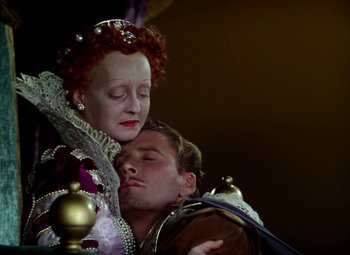 Movie still from “The Private Lives of Elizabeth and Essex” (1939), directed by Michael Curtiz – A man and a woman are embracing in a scene; Medium shot, High angle