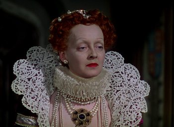 Movie still from “The Private Lives of Elizabeth and Essex” (1939), directed by Michael Curtiz – An older woman with red curly hair wearing a pink dress; Close Up shot, High angle