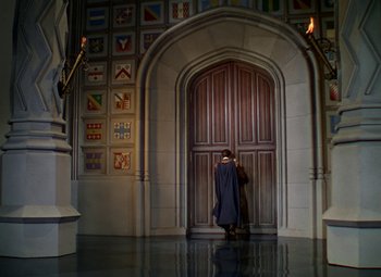 Movie still from “The Private Lives of Elizabeth and Essex” (1939), directed by Michael Curtiz – A person standing in front of an open door; Wide shot, High angle