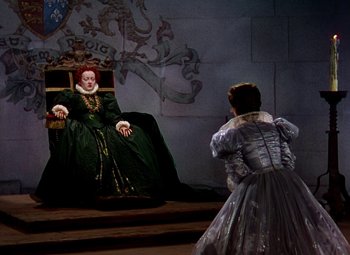 Movie still from “The Private Lives of Elizabeth and Essex” (1939), directed by Michael Curtiz – A woman dressed in medieval garb is being watched by another woman; Wide shot, High angle