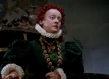 Movie still from “The Private Lives of Elizabeth and Essex” (1939), directed by Michael Curtiz – A woman with red hair wearing a green dress; Close Up shot, High angle