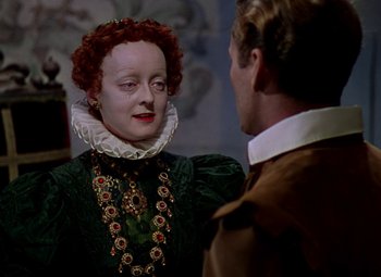 Movie still from “The Private Lives of Elizabeth and Essex” (1939), directed by Michael Curtiz – A man and a woman in a green dress; Close Up shot, Over the shoulder angle