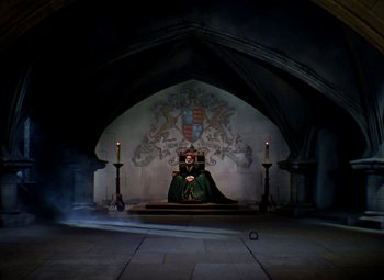 Movie still from “The Private Lives of Elizabeth and Essex” (1939), directed by Michael Curtiz – A man sitting on a throne in a castle; Wide shot, High angle